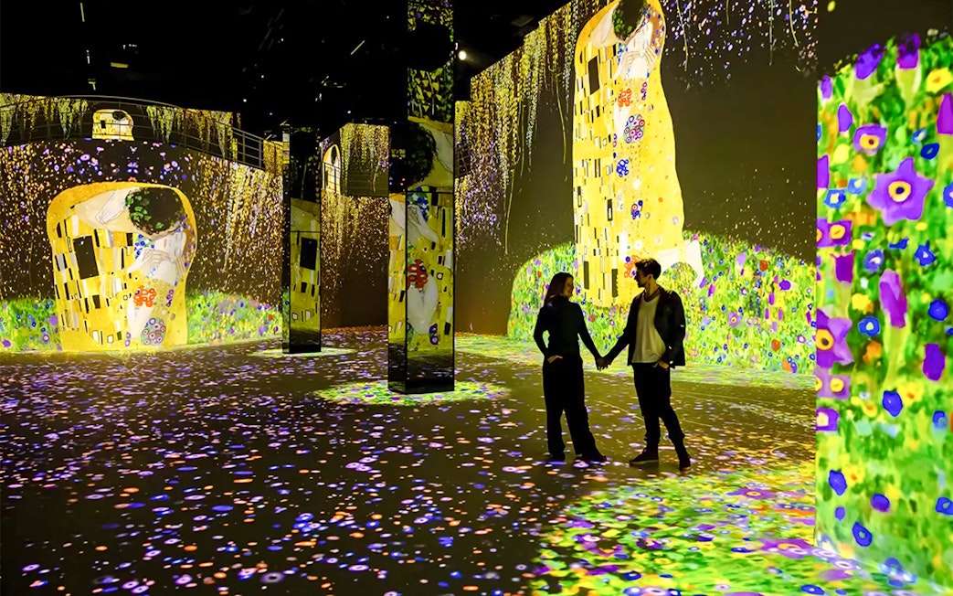 Gustav Klimt digital art display at Port des Lumières, Hamburg, with visitors exploring.