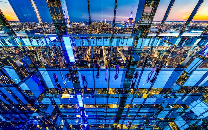 Guests exploring mirrored observation deck at Summit One Vanderbilt with New York City skyline at night.