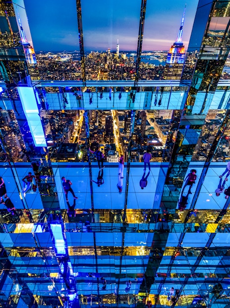 Guests exploring mirrored observation deck at Summit One Vanderbilt with New York City skyline at night.