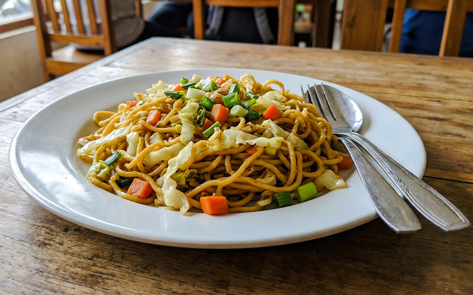 Indonesian fried noodles with vegetables on a white plate.