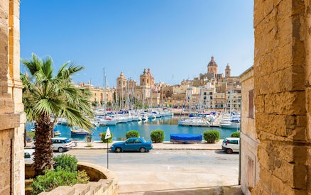 Boats docked in a marina with historic buildings in the Three Fortified Cities, Malta.