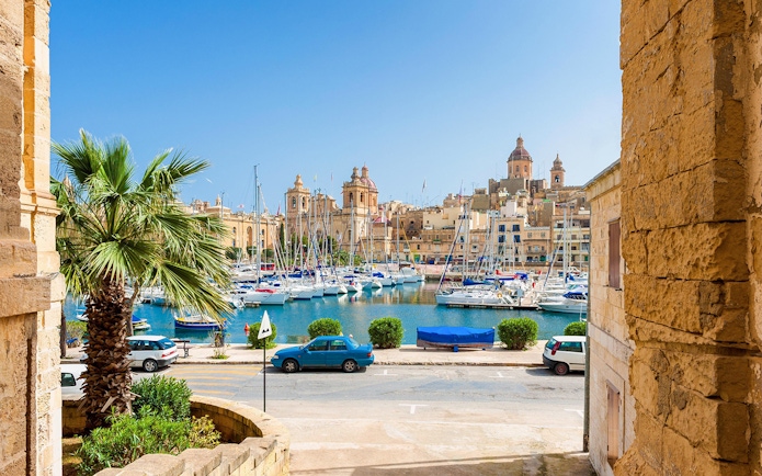 Boats docked in a marina with historic buildings in the Three Fortified Cities, Malta.