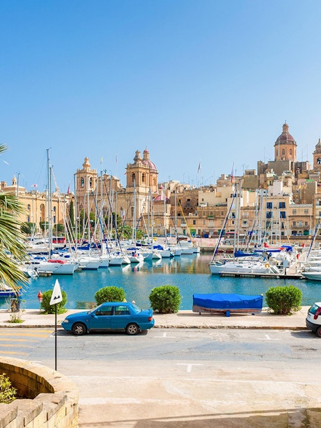Boats docked in a marina with historic buildings in the Three Fortified Cities, Malta.