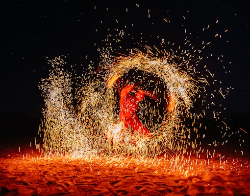 Fire show performer in Dubai desert during luxury safari tour.