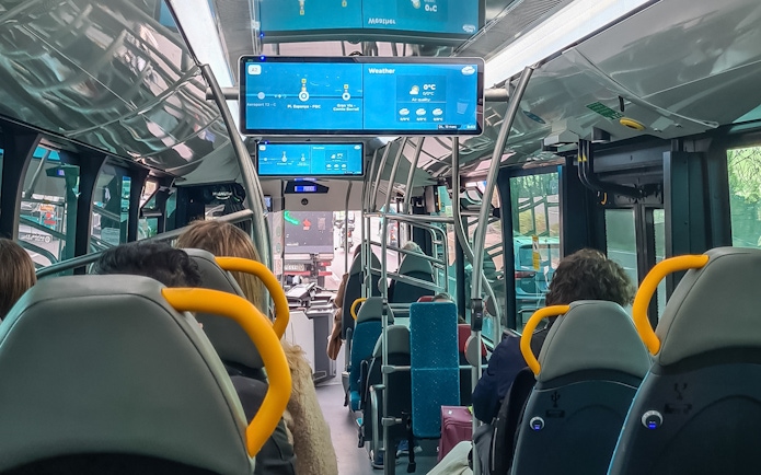 Barcelona Aerobus interior with passengers seated and digital screens displaying route information.