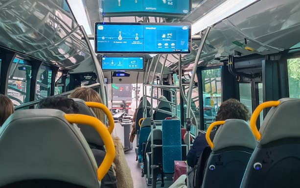 Barcelona Aerobus interior with passengers seated and digital screens displaying route information.