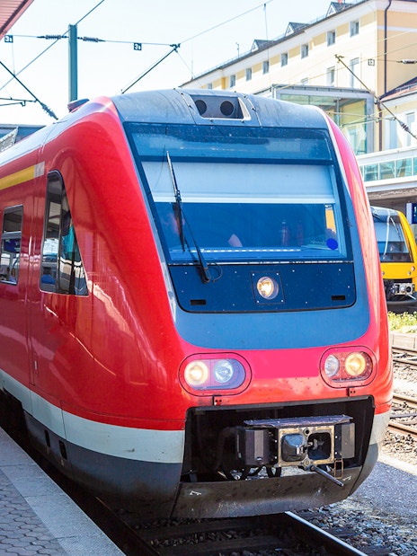 Red train at Munich station platform, part of Munich City Pass with public transportation.