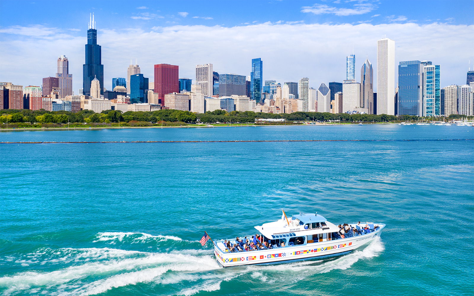 Sightseeing cruise boat on Chicago River with city skyline in background.