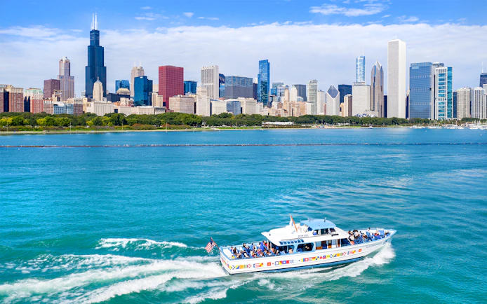 Sightseeing cruise boat on Chicago River with city skyline in background.