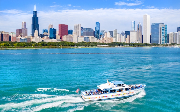 Sightseeing cruise boat on Chicago River with city skyline in background.