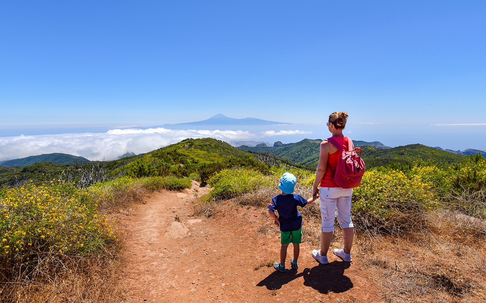 Mother and child hiking in Teide National Park with Mount Teide in the distance.