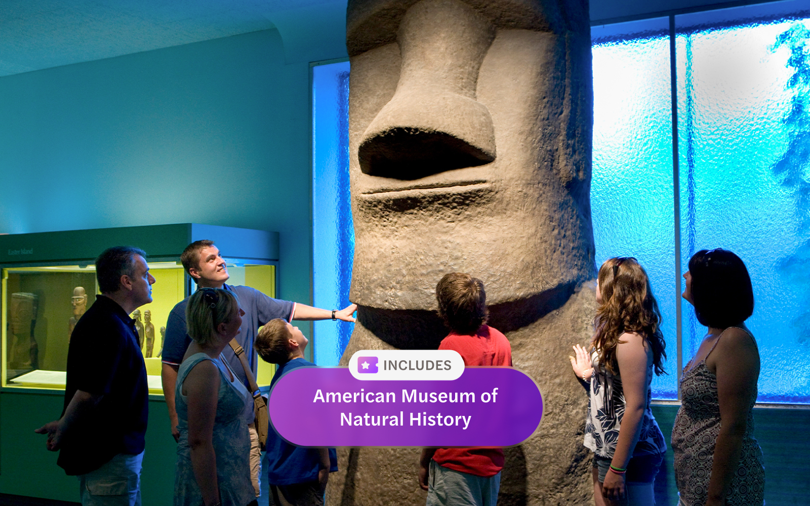 Visitors observing Easter Island statue at American Museum of Natural History exhibit.
