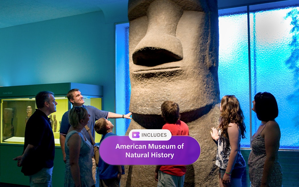Visitors observing Easter Island statue at American Museum of Natural History exhibit.