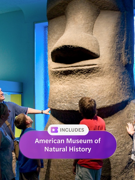 Visitors observing Easter Island statue at American Museum of Natural History exhibit.