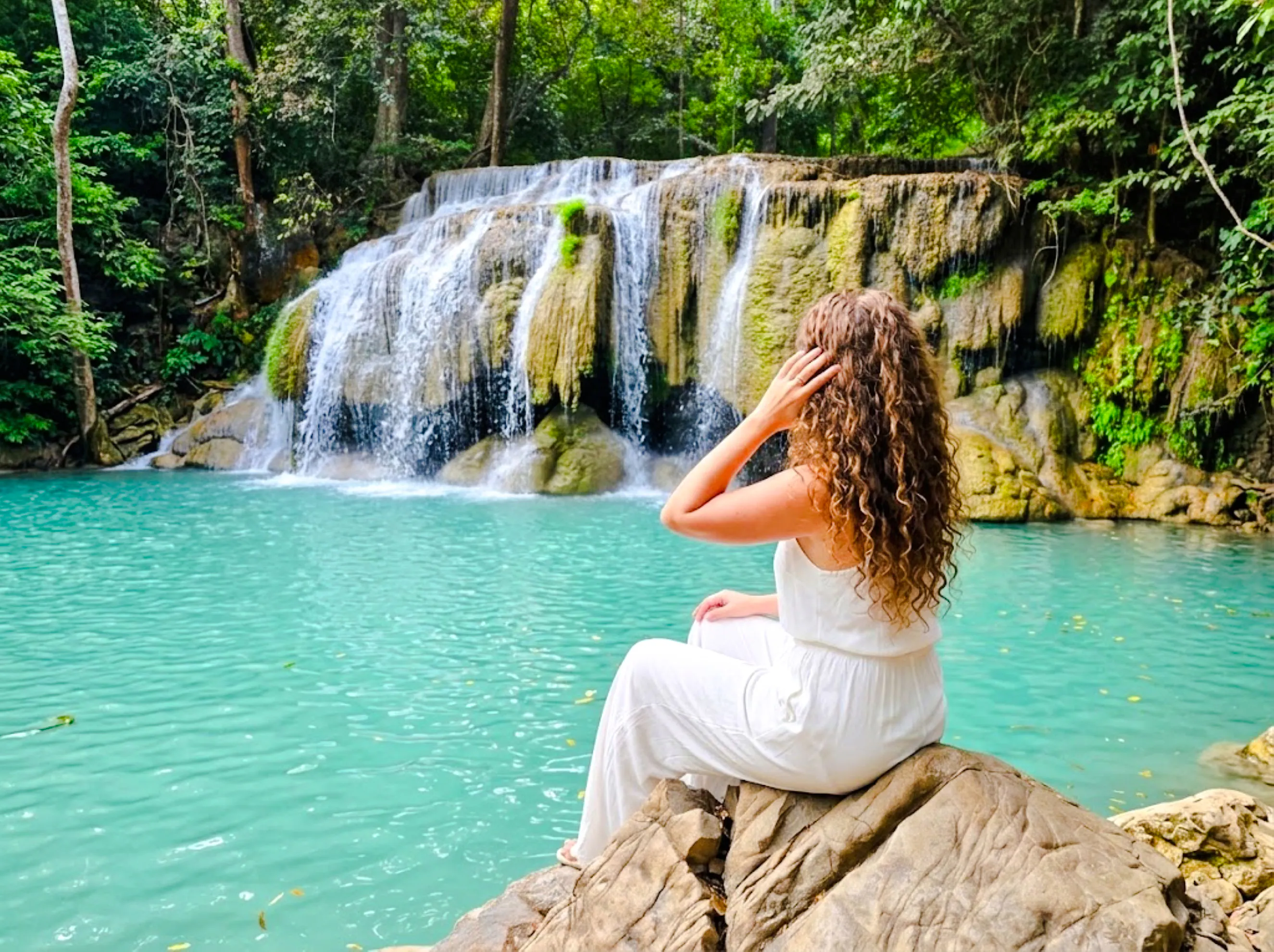 Visitor admiring Erawan Waterfall in Kanchanaburi, surrounded by lush greenery.