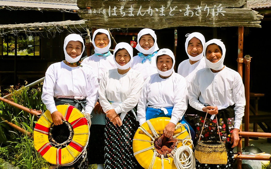 Ama divers in traditional attire holding flotation devices in Japan.