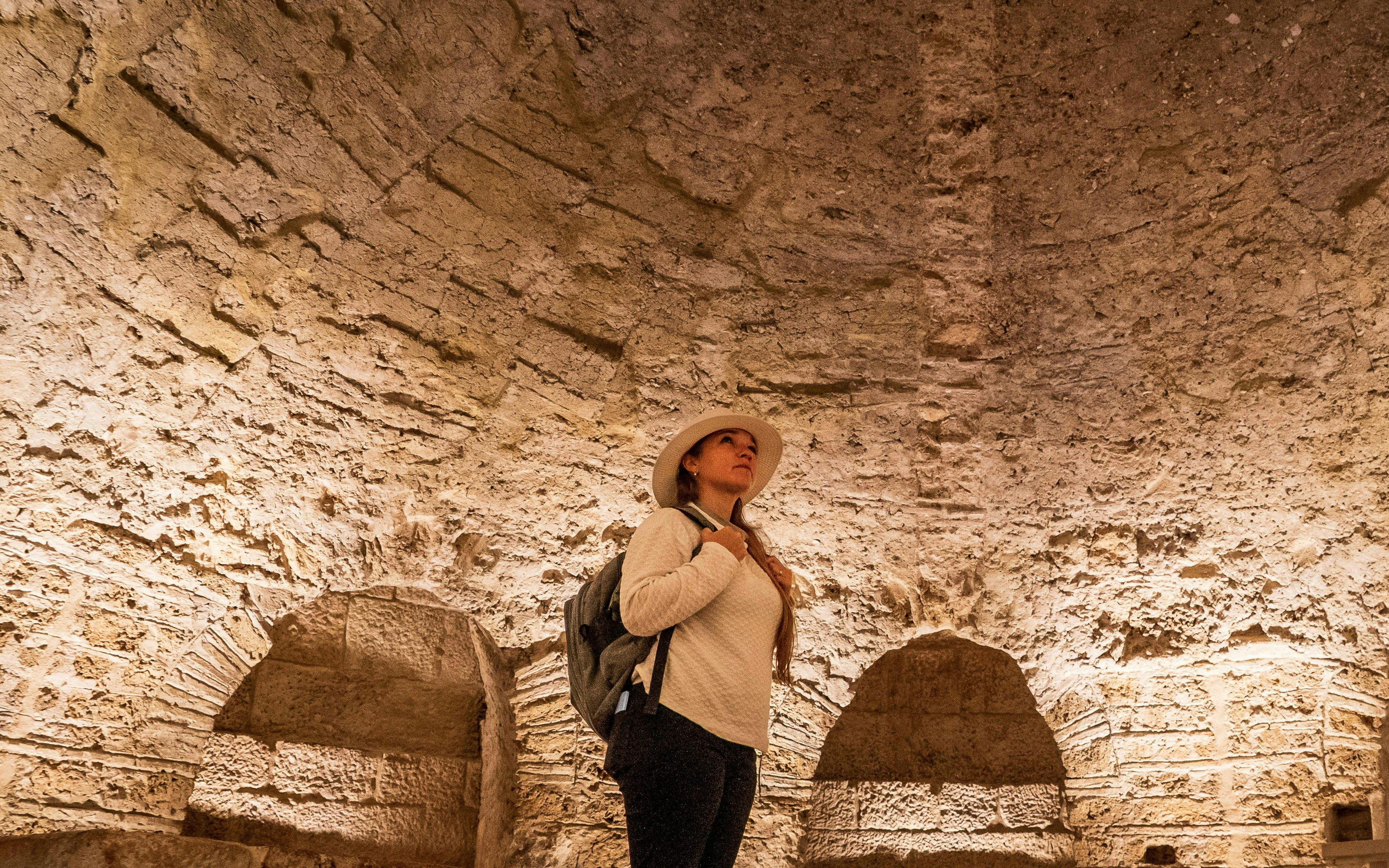 Woman exploring ancient stone vault interior.