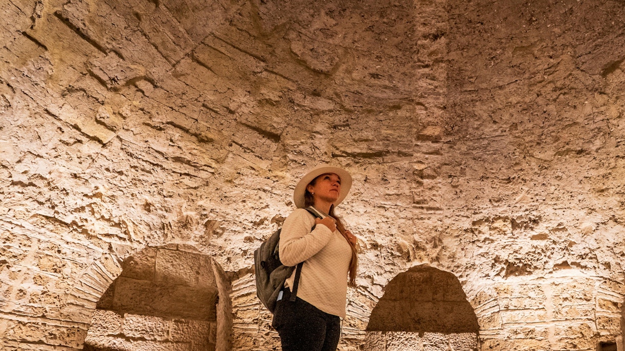 Woman exploring ancient stone vault interior.