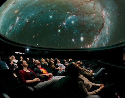 Visitors watching a starry sky projection inside the Royal Observatory Planetarium.