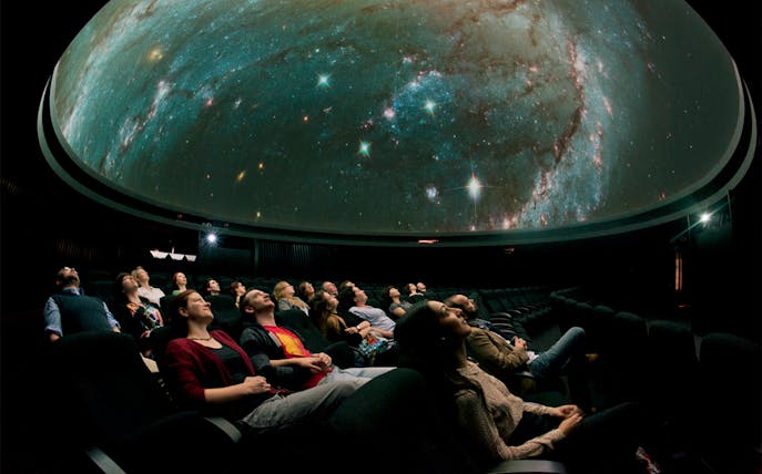 Visitors watching a starry sky projection inside the Royal Observatory Planetarium.