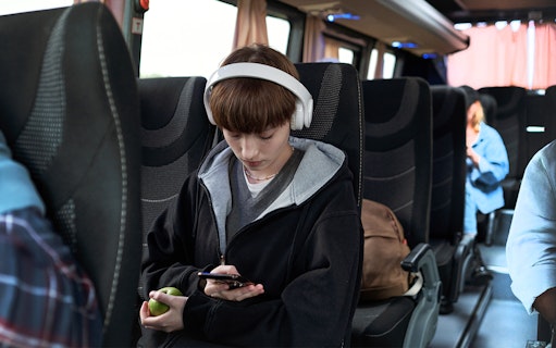 Young girl with headphones using phone on bus from Pisa to Florence.