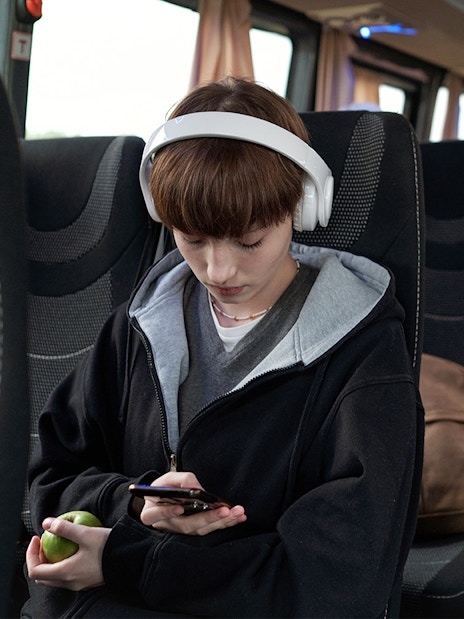 Young girl with headphones using phone on bus from Pisa to Florence.