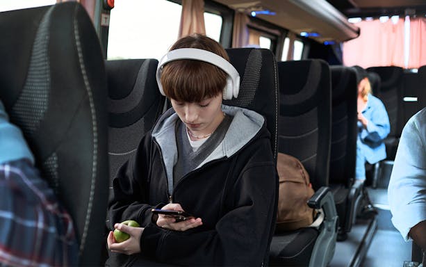 Young girl with headphones using phone on bus from Pisa to Florence.