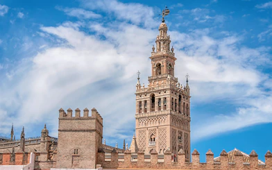 Seville Cathedral's La Giralda tower under a blue sky.