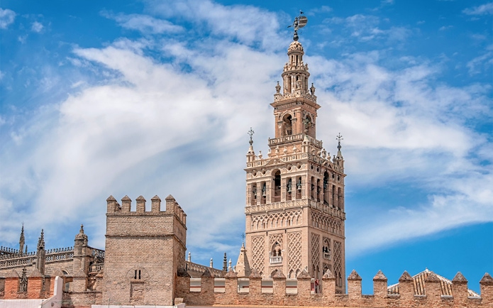 Seville Cathedral's La Giralda tower under a blue sky.