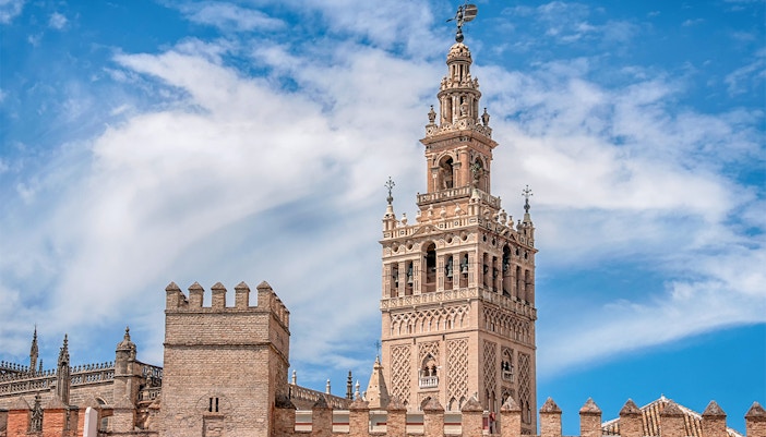 Seville Cathedral's La Giralda tower under a blue sky.
