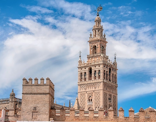 Seville Cathedral's La Giralda tower under a blue sky.