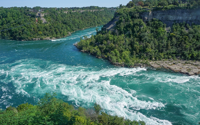Whirlpool Rapids in Niagara River, surrounded by lush greenery, Ontario, Canada.