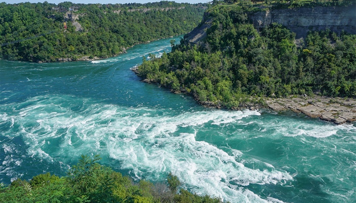 Whirlpool Rapids in Niagara River, Ontario, Canada, showcasing turbulent waters and surrounding gorge.