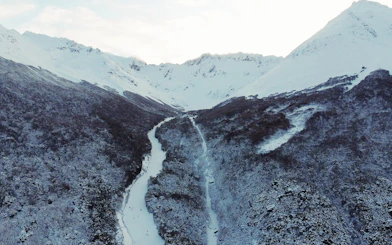 Aerial view of snow-covered Ushuaia Martial Glacier with winding path through forest.