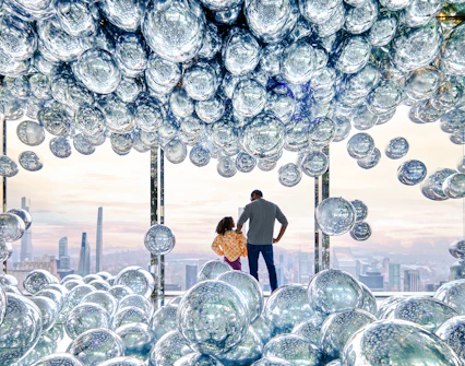 Visitors at SUMMIT One Vanderbilt observation deck with reflective spheres, New York City skyline in view.