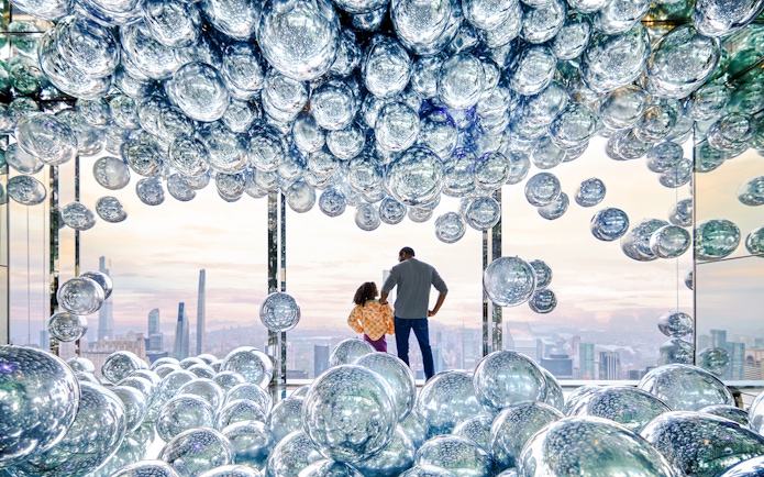 Visitors at SUMMIT One Vanderbilt observation deck with reflective spheres, New York City skyline in view.