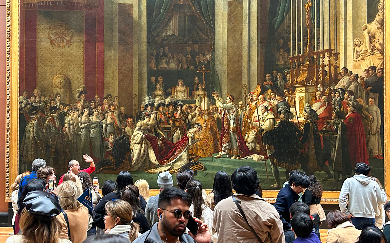 Tourists viewing "The Coronation of Napoleon" painting at the Louvre Museum, Paris.