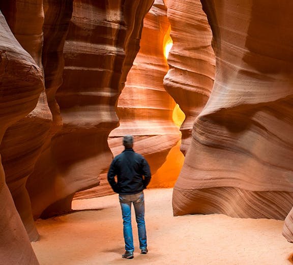Man exploring the narrow sandstone walls of Antelope Canyon, Ligai Si Anii Canyon.