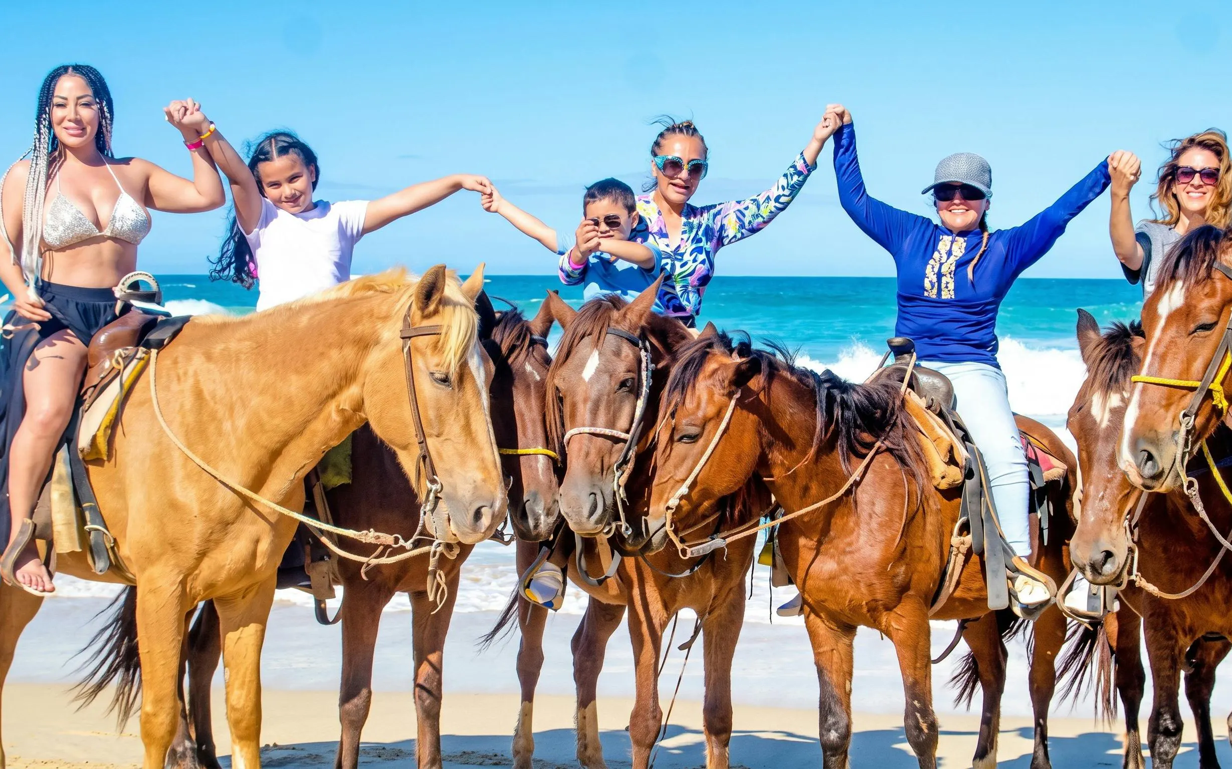 Group horseback riding on Macao Beach with ocean backdrop.