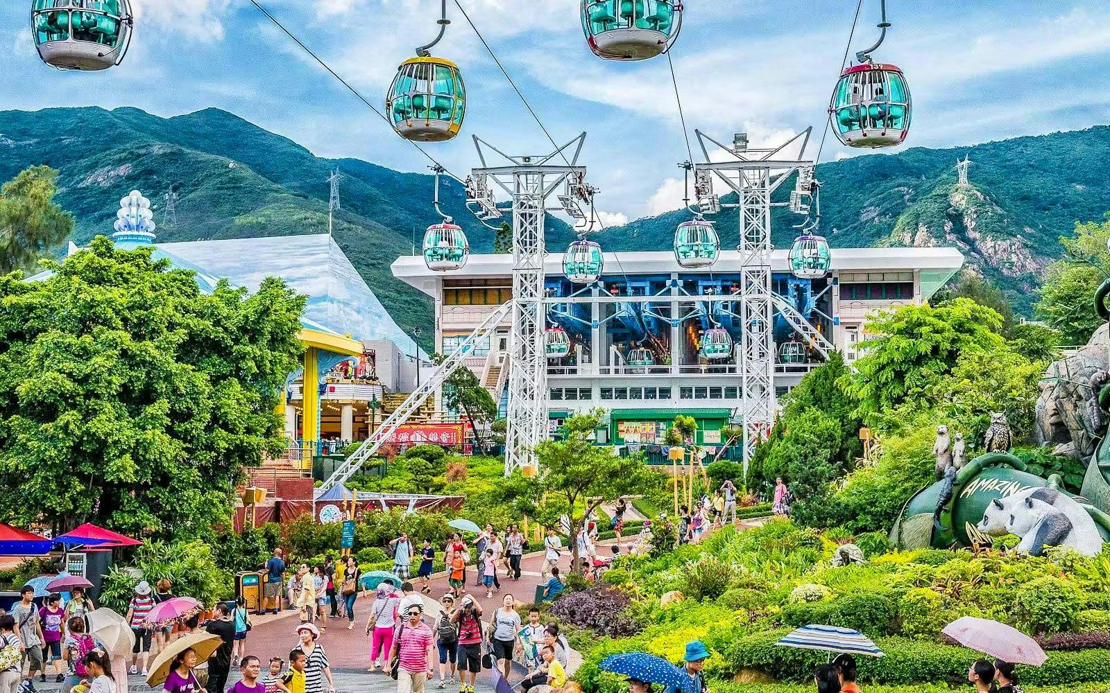 Cable cars above Ocean Park Hong Kong with lush greenery and visitors below.