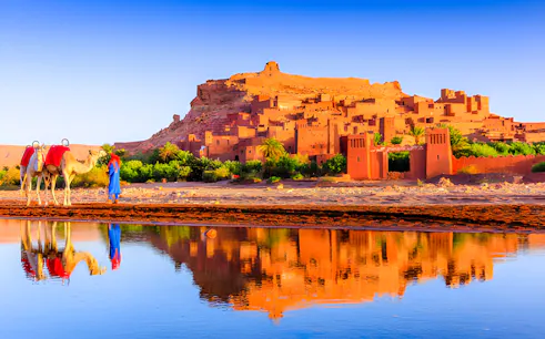 Camel and guide near Kasbah Ait Ben Haddou, reflecting in water, on a private trip from Marrakech.