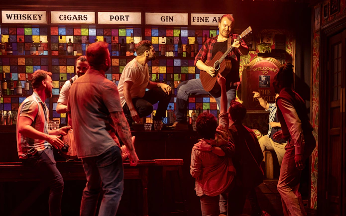 Men performing on stage with a guitar at The Choir of Man show.