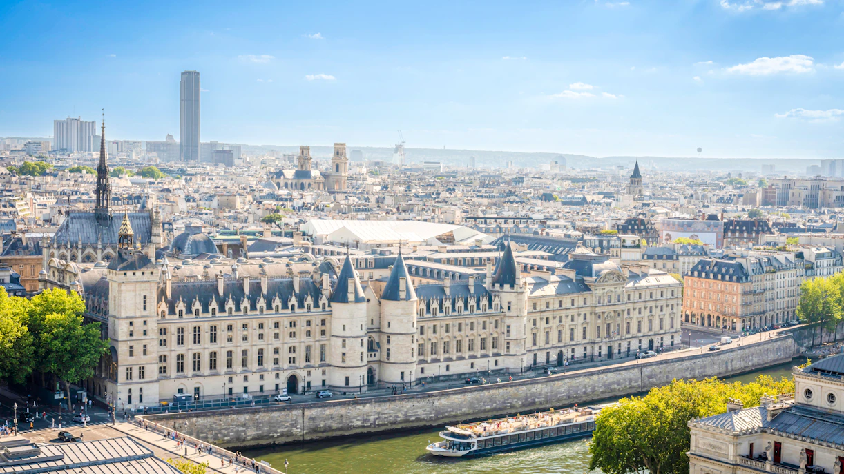 Conciergerie towers along the Seine River in Paris, with cityscape in the background.
