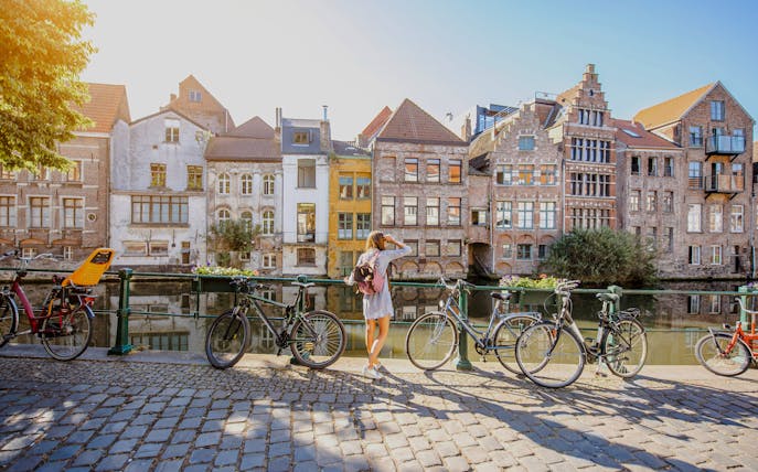 Guest by Ghent canal with historic buildings and bicycles.