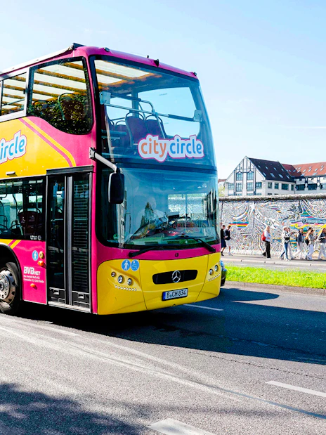 City Circle bus passing by the Berlin Wall with colorful murals.