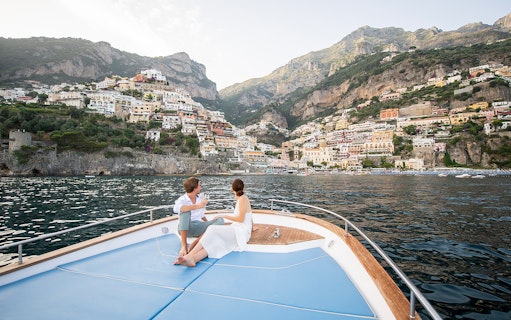 Couple enjoying a boat tour with a view of Positano on the Amalfi Coast.