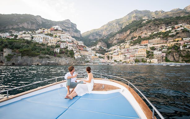 Couple enjoying a boat tour with a view of Positano on the Amalfi Coast.