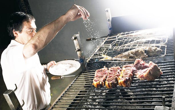 Grilling meat and fish at a cider house during a guided tour from San Sebastian.