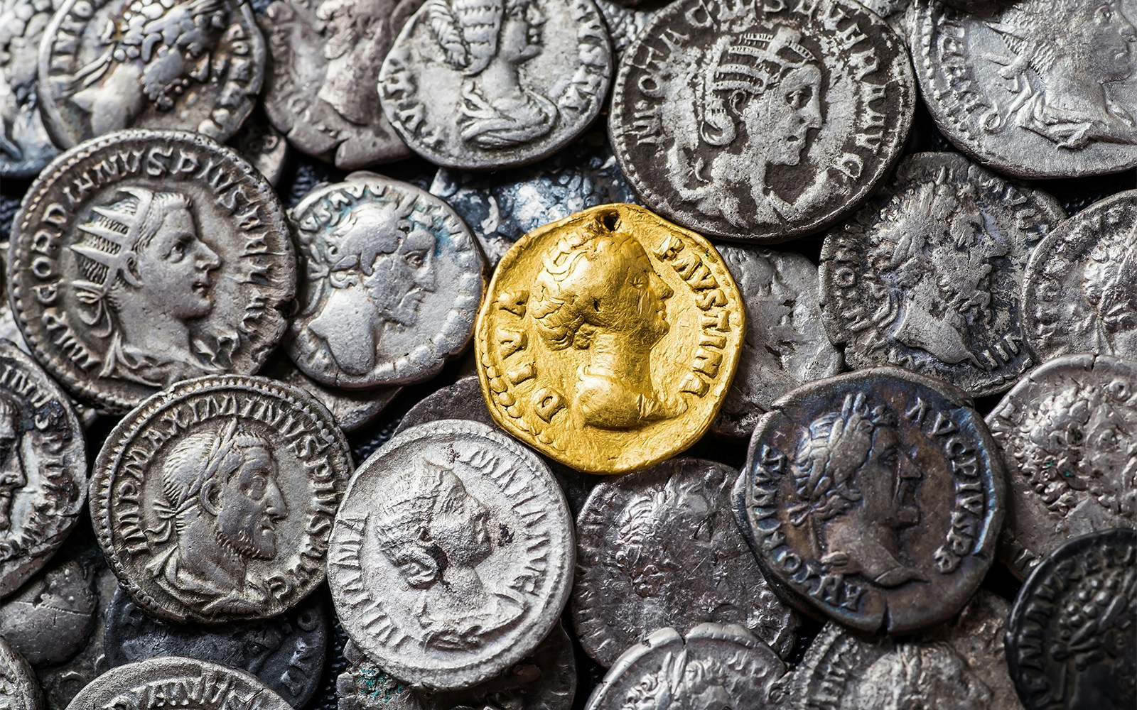 Roman Empire gold and silver coins displayed on a dark surface.