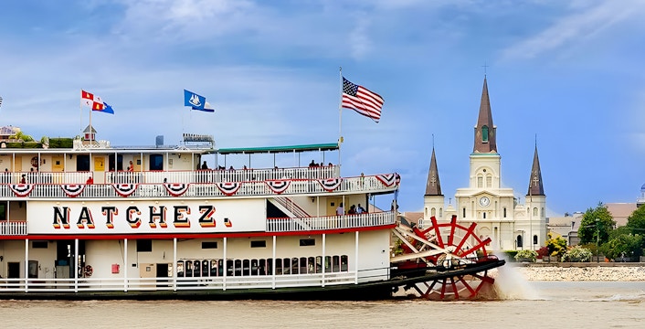 Steamboat Natchez sailing on the Mississippi River with the city in the background.